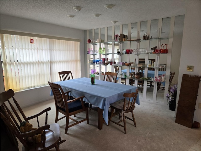 dining room featuring a textured ceiling and light carpet