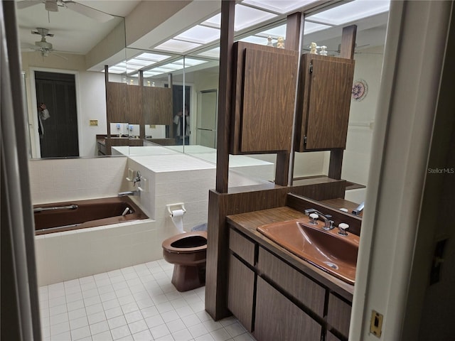 bathroom with tile patterned flooring, toilet, vanity, ceiling fan, and tiled tub