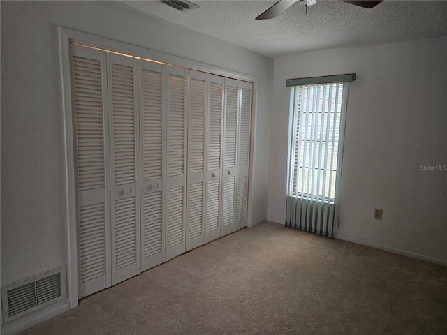 unfurnished bedroom featuring ceiling fan, a closet, carpet floors, and a textured ceiling