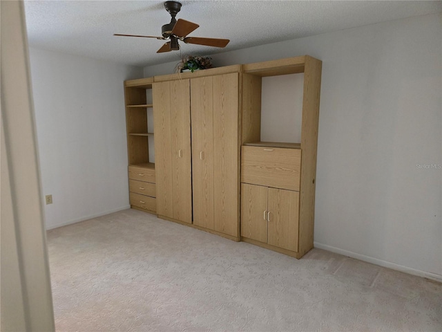 unfurnished bedroom with ceiling fan, light colored carpet, and a textured ceiling