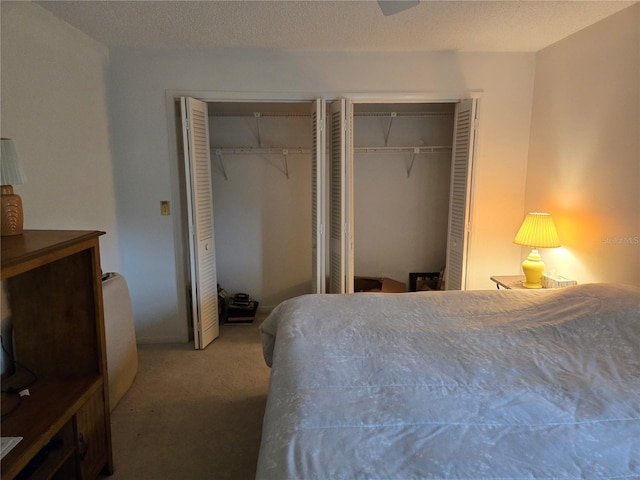 carpeted bedroom featuring multiple closets and a textured ceiling