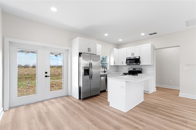 kitchen with a sink, visible vents, white cabinetry, appliances with stainless steel finishes, and a center island