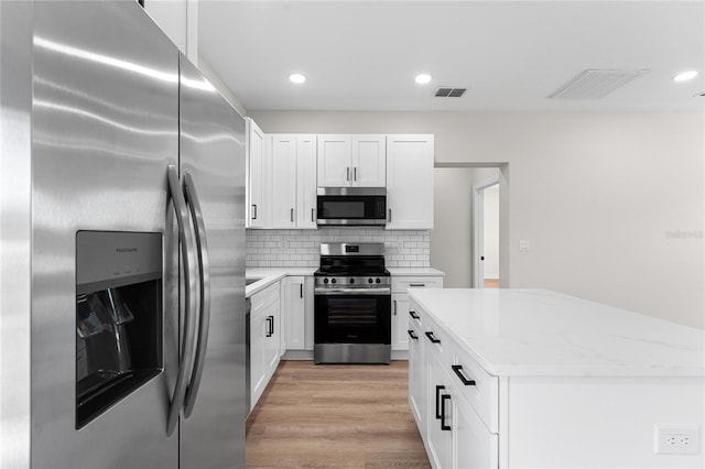 kitchen featuring stainless steel appliances, tasteful backsplash, visible vents, white cabinets, and light wood-type flooring