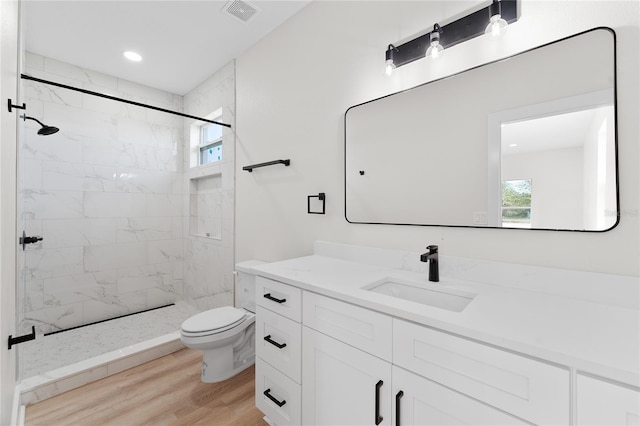 full bath featuring a stall shower, visible vents, toilet, wood finished floors, and vanity