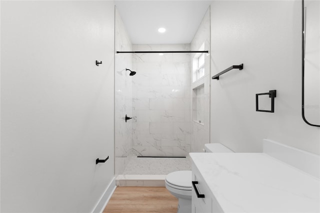 bathroom with toilet, vanity, a shower stall, wood finished floors, and baseboards