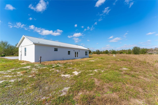 rear view of house featuring metal roof and a yard