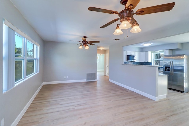 kitchen with appliances with stainless steel finishes, white cabinetry, light wood-type flooring, and kitchen peninsula