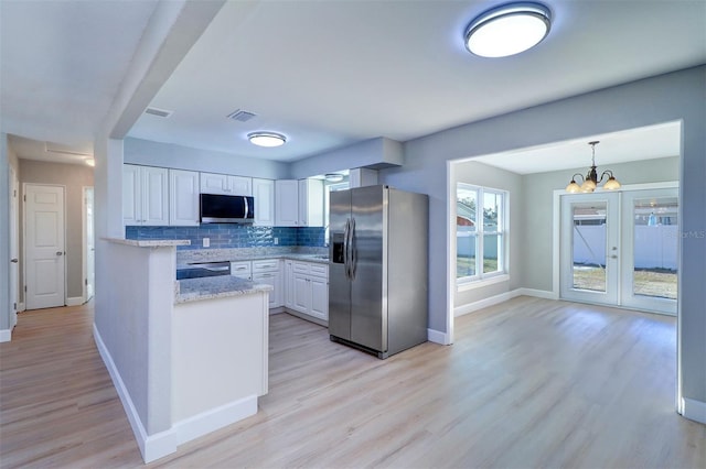 kitchen with a chandelier, hanging light fixtures, decorative backsplash, white cabinets, and appliances with stainless steel finishes