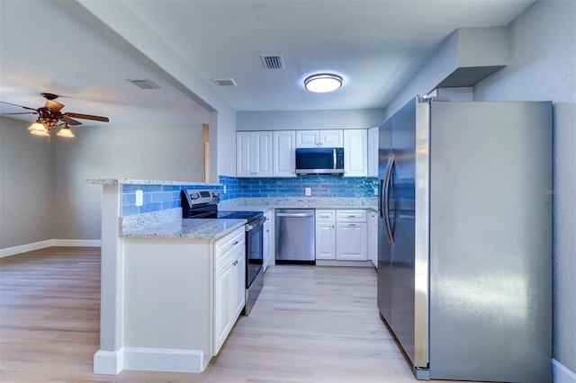 kitchen featuring light stone counters, kitchen peninsula, stainless steel appliances, decorative backsplash, and white cabinetry