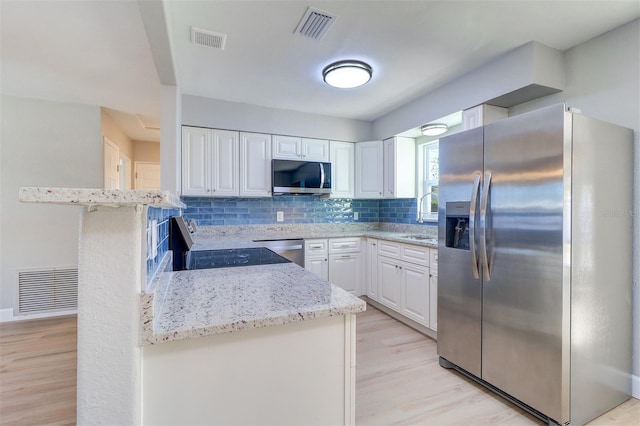 kitchen with stainless steel appliances, sink, white cabinetry, tasteful backsplash, and light stone countertops