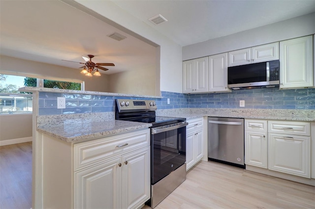 kitchen featuring stainless steel appliances, light wood-type flooring, light stone countertops, white cabinets, and backsplash