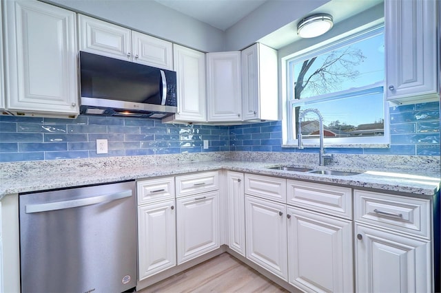 kitchen featuring sink, stainless steel appliances, white cabinetry, and light stone counters