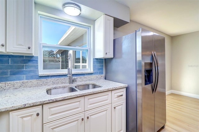 kitchen with white cabinetry, sink, light stone counters, and stainless steel fridge with ice dispenser