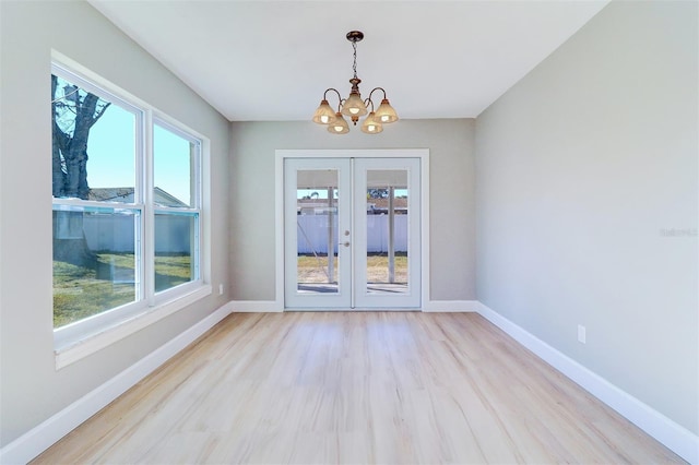 unfurnished room featuring a notable chandelier, a healthy amount of sunlight, and light hardwood / wood-style floors