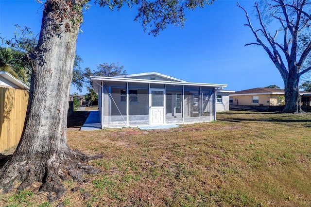 back of property with a lawn and a sunroom