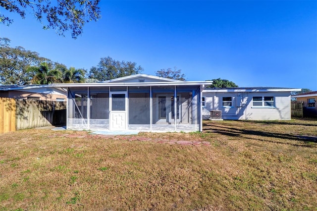 rear view of property with a yard, central air condition unit, and a sunroom