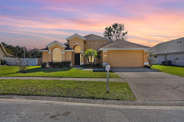 view of front of home with central AC, a garage, and a lawn