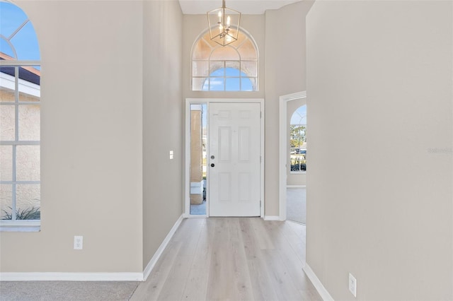 entrance foyer featuring light hardwood / wood-style floors, a high ceiling, and an inviting chandelier