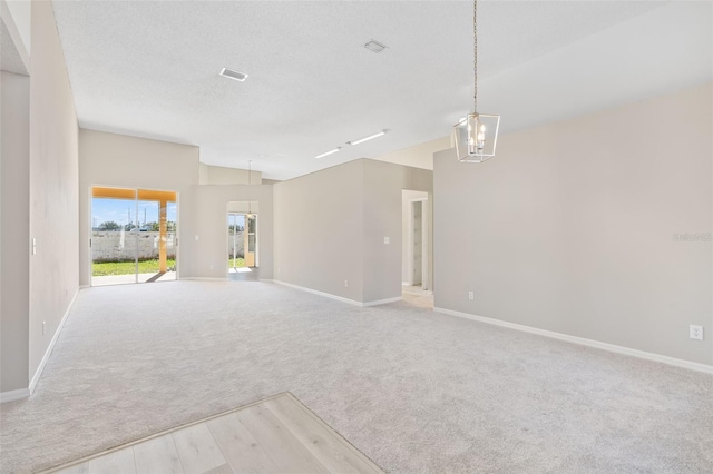 carpeted spare room featuring a chandelier