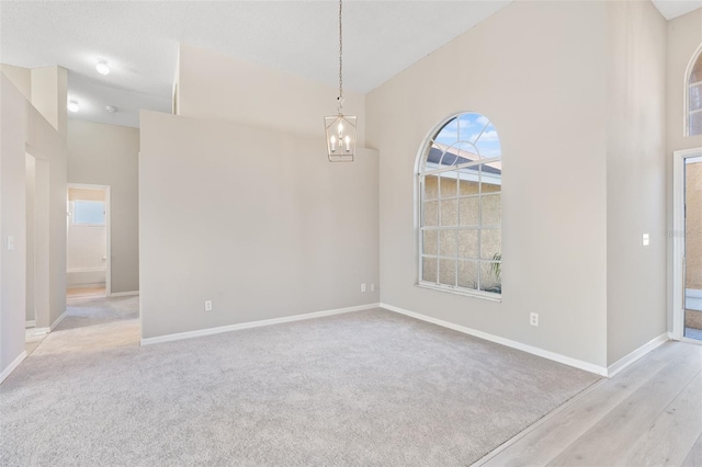 unfurnished room featuring light wood-type flooring and an inviting chandelier