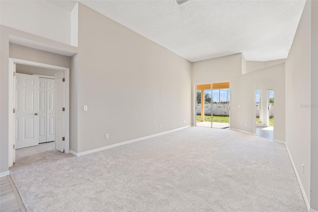 carpeted empty room featuring a textured ceiling and a high ceiling