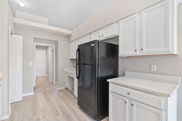 kitchen featuring white cabinetry, black fridge, and light hardwood / wood-style flooring