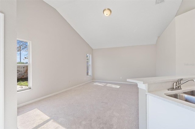 interior space featuring carpet, vaulted ceiling, a wealth of natural light, and sink