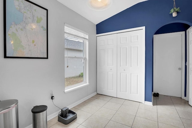 unfurnished bedroom featuring a closet, lofted ceiling, and light tile patterned floors