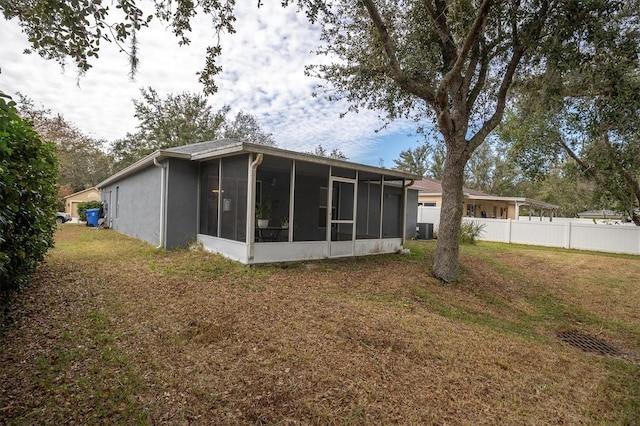 rear view of property with central AC, a yard, and a sunroom