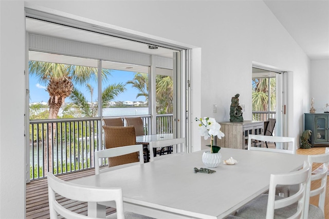 dining room featuring vaulted ceiling, a water view, and a wealth of natural light