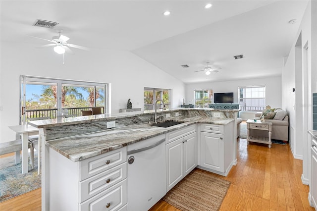 kitchen featuring white cabinetry, sink, dishwashing machine, light stone counters, and a center island with sink