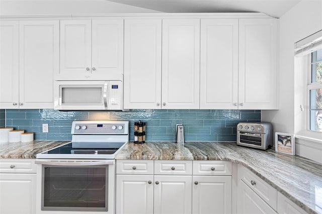 kitchen with backsplash, white appliances, light stone counters, and white cabinets