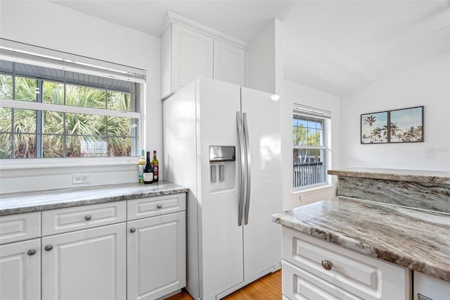 kitchen featuring light hardwood / wood-style floors, light stone countertops, white fridge with ice dispenser, and white cabinets