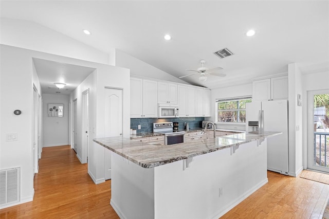 kitchen with lofted ceiling, white appliances, white cabinetry, and visible vents