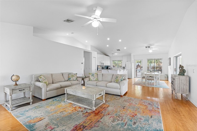 living area featuring vaulted ceiling, a ceiling fan, visible vents, and light wood-style floors