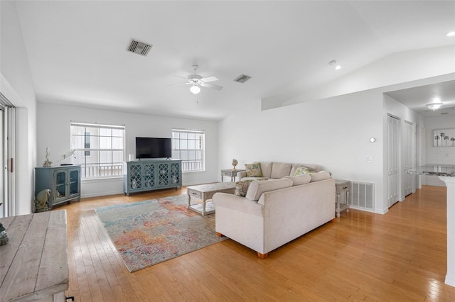 living room featuring lofted ceiling, light wood finished floors, and visible vents