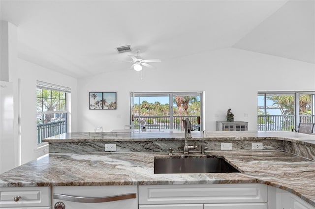 kitchen with lofted ceiling, white cabinetry, and a sink