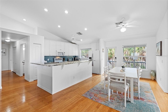 kitchen featuring white appliances, a kitchen island with sink, white cabinetry, and a ceiling fan