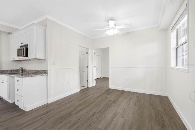 interior space featuring ceiling fan, ornamental molding, dark wood-style flooring, and a sink