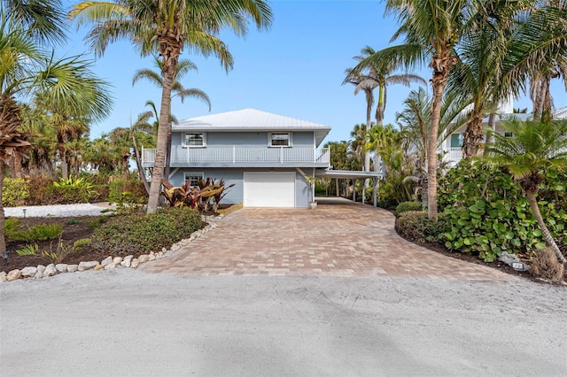 view of front facade with a garage, a carport, decorative driveway, and a balcony