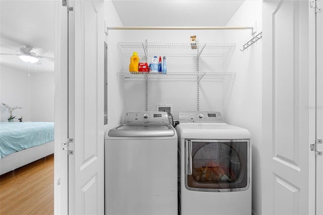 washroom featuring a ceiling fan, laundry area, washing machine and clothes dryer, and wood finished floors