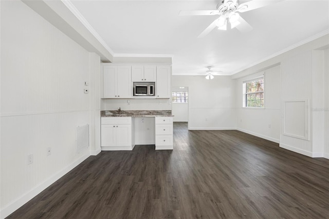 kitchen featuring visible vents, stainless steel microwave, crown molding, white cabinetry, and a sink