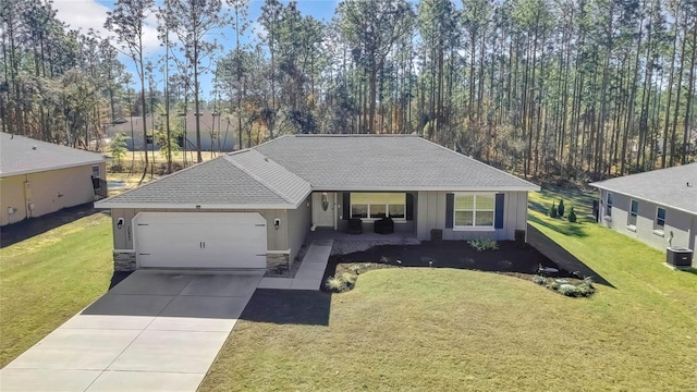 view of front of house featuring a garage, central air condition unit, and a front lawn