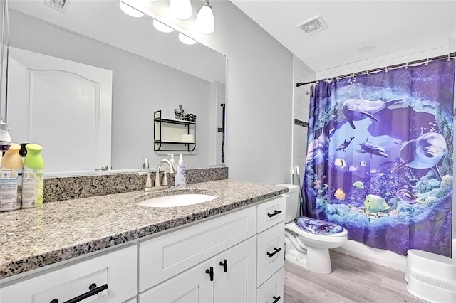 bathroom with hardwood / wood-style floors, vanity, curtained shower, and toilet