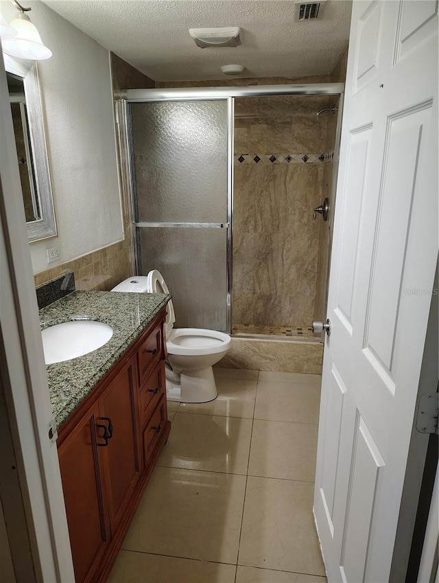 bathroom with a shower with shower door, vanity, tile patterned floors, and a textured ceiling