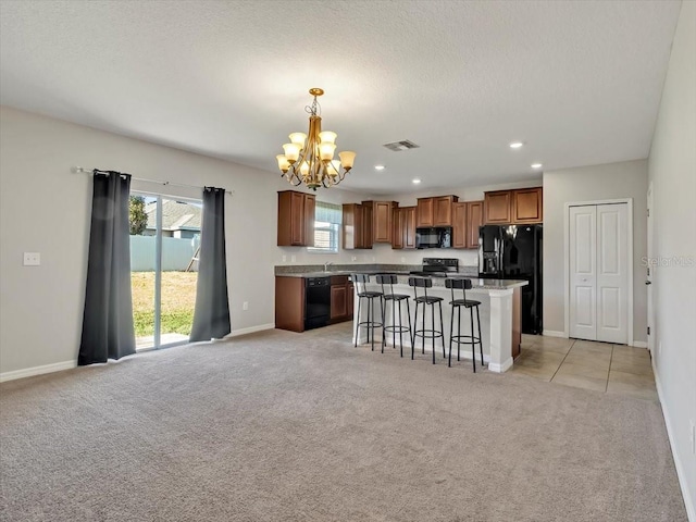 kitchen with pendant lighting, light colored carpet, a kitchen island, and black appliances