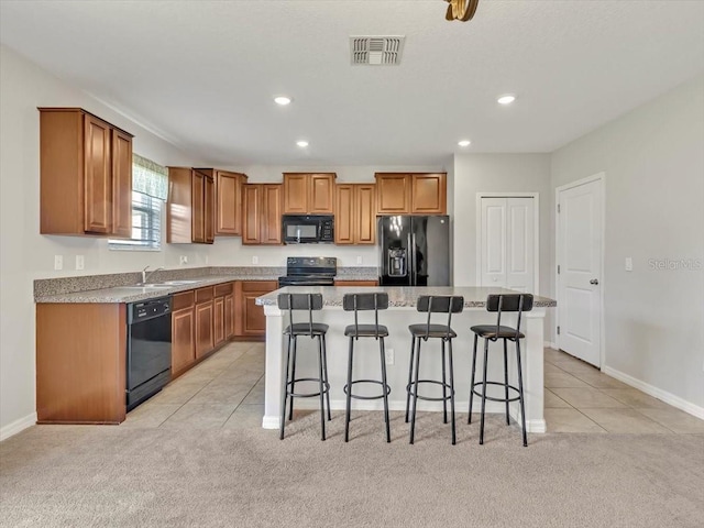 kitchen with light carpet, a breakfast bar, sink, black appliances, and a center island