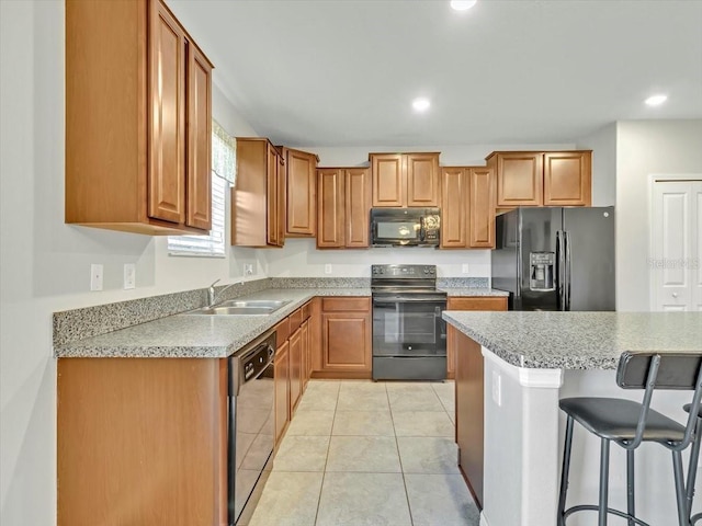 kitchen featuring sink, light stone counters, a kitchen bar, light tile patterned floors, and black appliances