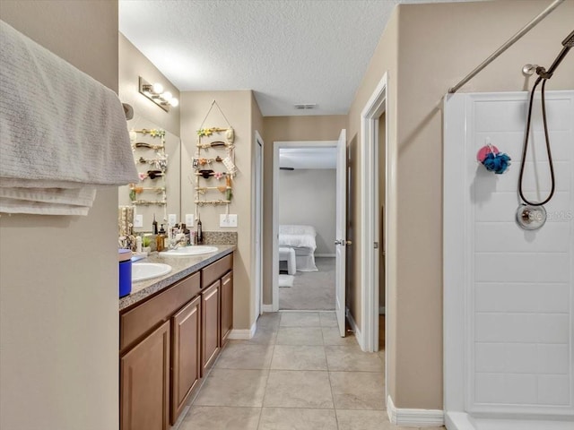 bathroom featuring tile patterned flooring, a textured ceiling, vanity, and walk in shower