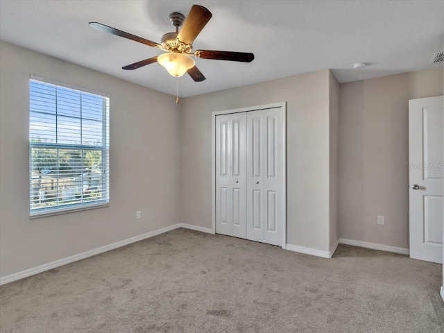 unfurnished bedroom with ceiling fan, a closet, and light colored carpet